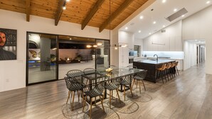 A modern kitchen with a central island, glass dining table, and chairs. - Luxury Camelback Mountain Views, Theater, Sauna, Heated Pool, Spa (Phoenix)