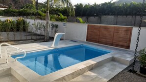 Une piscine rectangulaire dotée d’une plage blanche et d’un élément décoratif aquatique intégré.