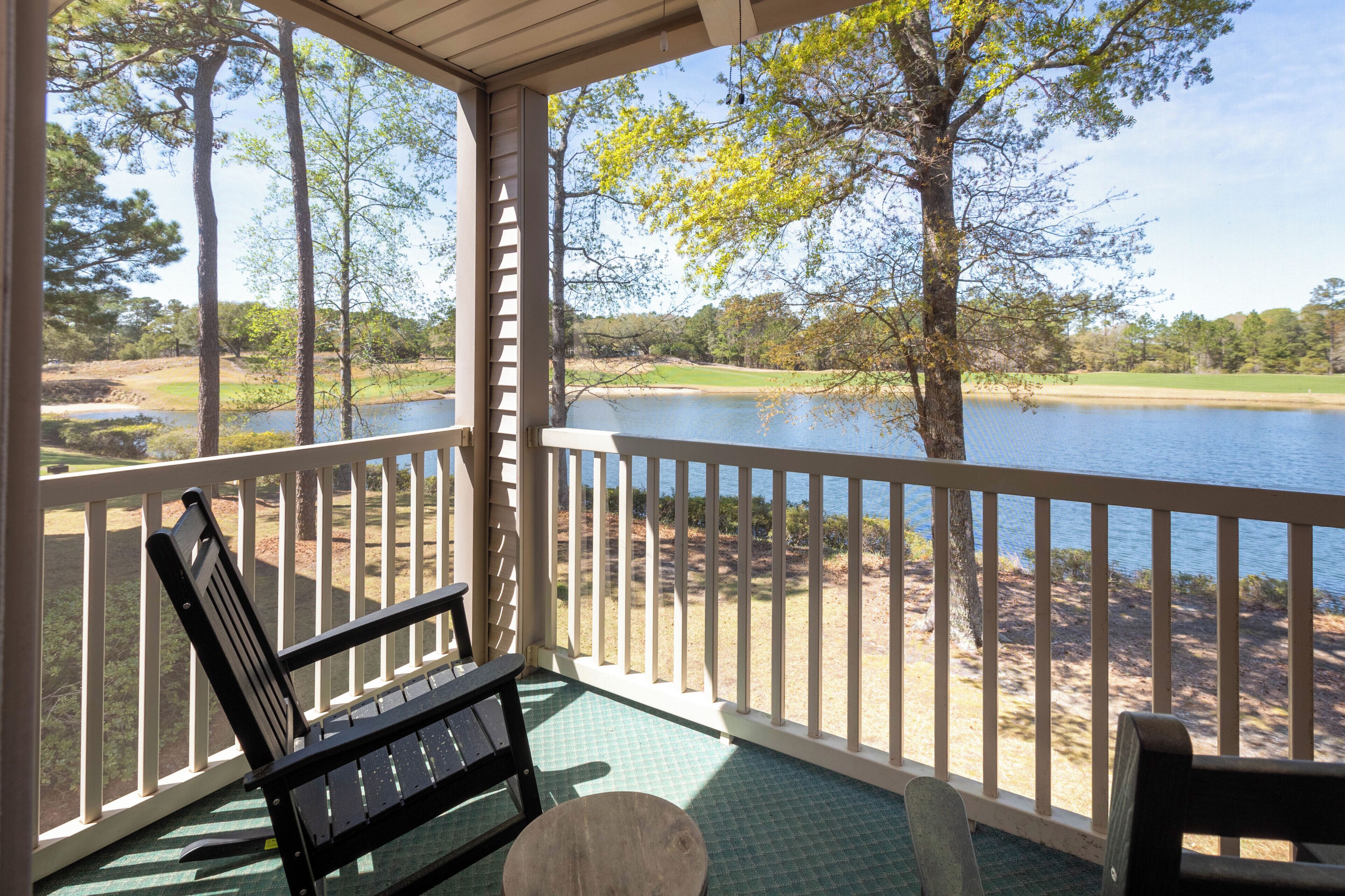 Un espacio al aire libre techado con un banco, una mesa y vistas a un lago y árboles.