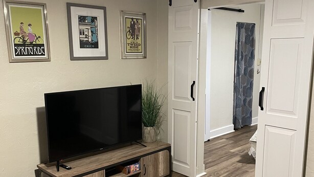 Ein Wohnzimmer mit Flachbildfernseher, einem farbenfrohen Teppich und einem Schiebetürenschrank.