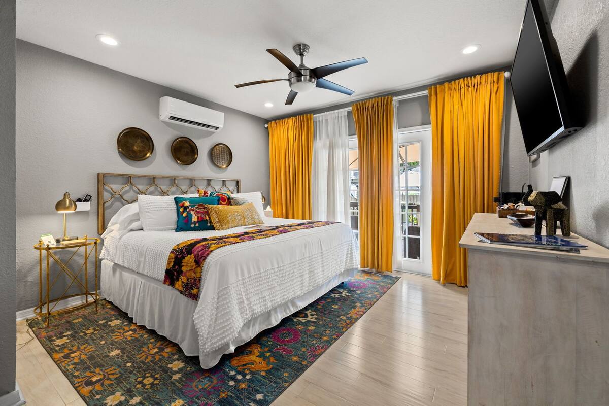 A modern bedroom with a bed, a desk, and a TV.
