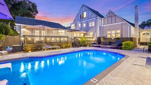 A backyard with a swimming pool, a wooden deck, and a house with a large window overlooking the pool. - The Kenwood Gables B&B (St. Petersburg)
