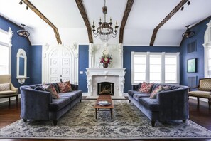 A living room with two sofas, a fireplace, and a chandelier. - The Kenwood Gables B&B (St. Petersburg)