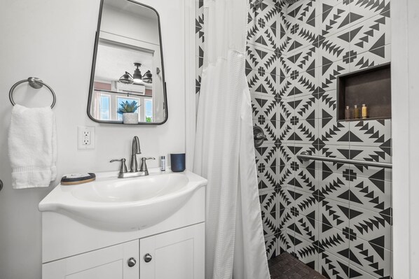 A bathroom with a white sink, a mirror, a towel ring, and a shower curtain. - The Kenwood Gables B&B (St. Petersburg)