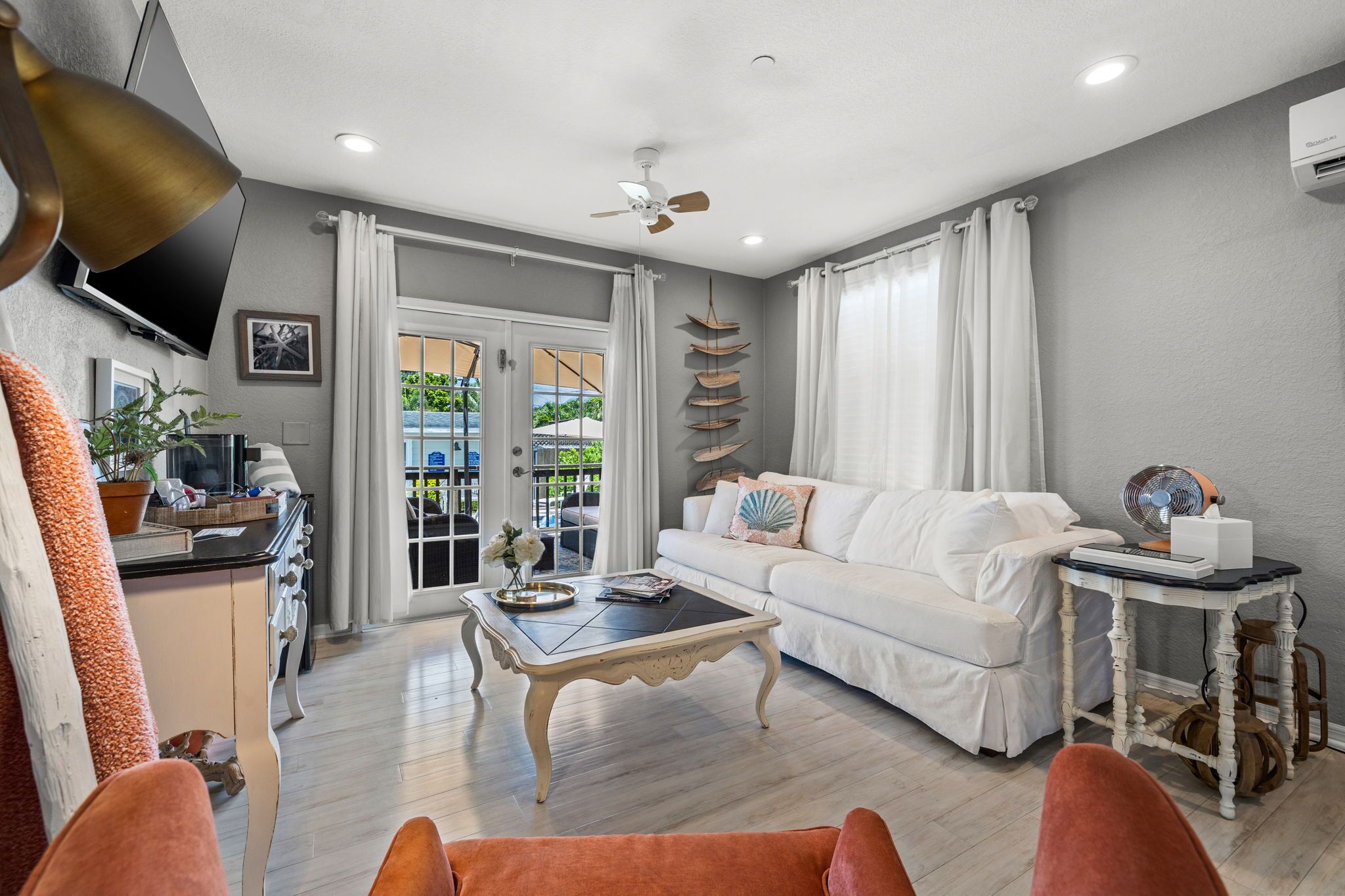 A spacious living room with a white sofa, a coffee table, and a television.