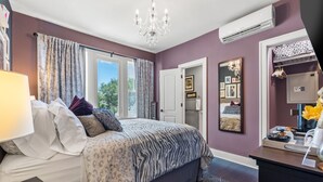 A bedroom with a bed, a desk, a mirror, and a window with curtains. - The Kenwood Gables B&B (St. Petersburg)