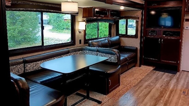 A cozy RV interior with a dining area, seating, and a TV.