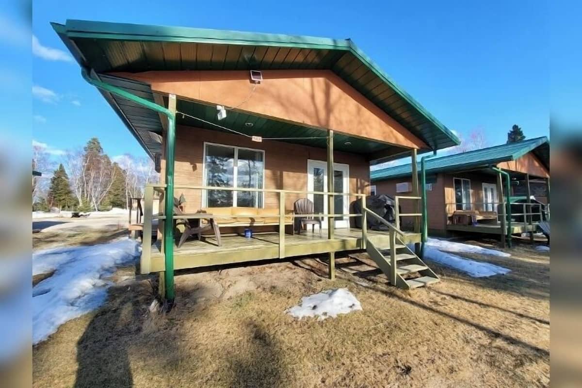 A wooden cabin with a green roof and a covered porch.