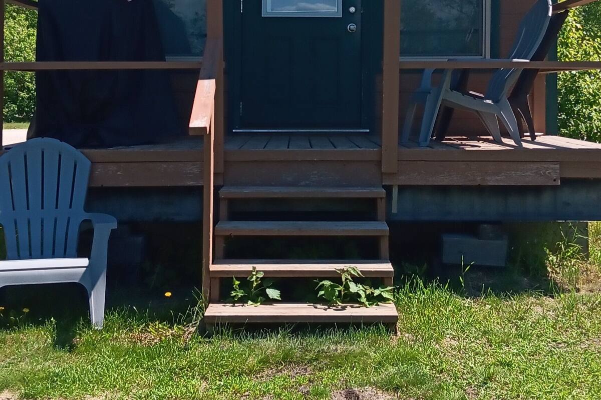 A small cabin with a front porch, two windows, and a door.