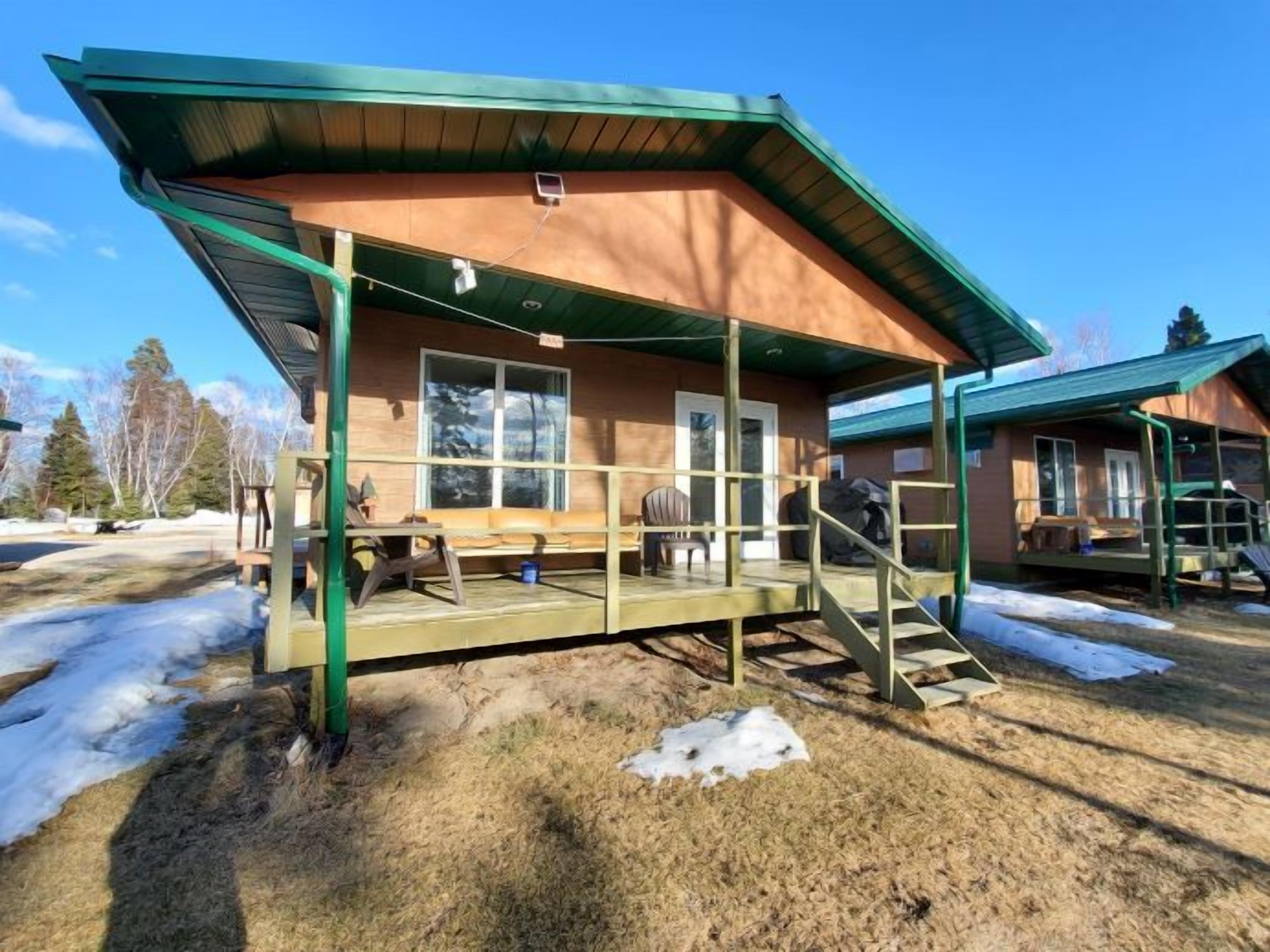 A cabin with a covered porch, wooden steps, and a bench.