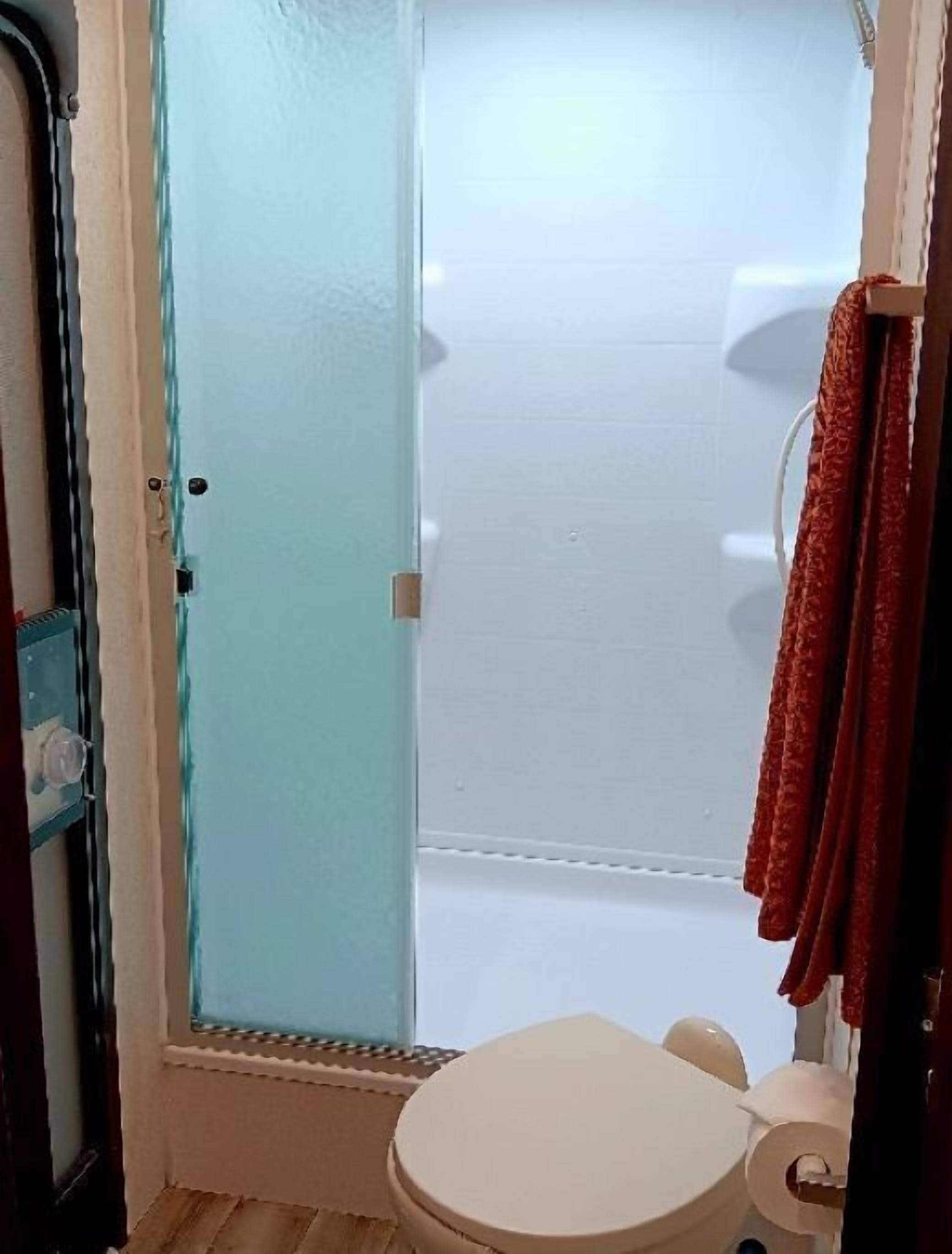 Une salle de bain avec des toilettes, une douche et une porte en verre.