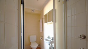 A bathroom with a toilet, sink, and mirror. - Caloundra Backpackers - Hostel (Caloundra)