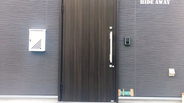 A dark wooden door with a handle, set against a textured wall with a sign reading "HOSTEL HIDE AWAY". - Hostel Hideaway (Tokyo)