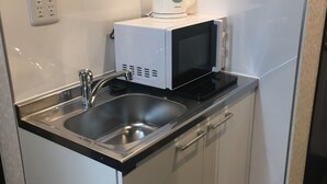 A compact kitchenette with a stainless steel sink, a microwave, and a coffee maker. - Hostel Hideaway (Tokyo)