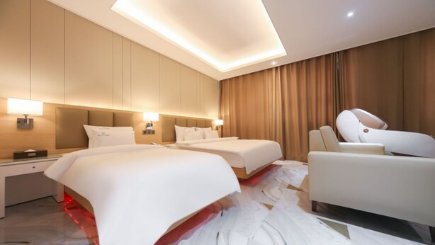 A modern hotel room with two beds, a sofa, and a massage chair. - Hotel Elysia Daegu (Daegu)