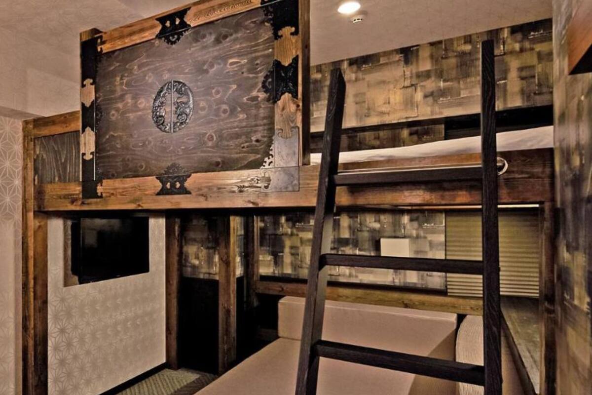 A bunk bed with a wooden headboard, a ladder, and a window.