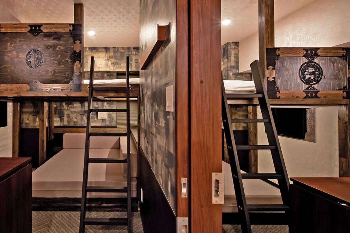 A compact room with bunk beds, a wooden desk, and a ladder.