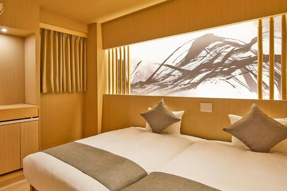 A hotel room with a large bed, a wooden headboard, and a wall-mounted artwork.