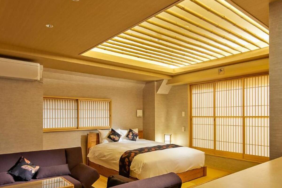 A modern hotel room with a bed, a sofa, and a desk.