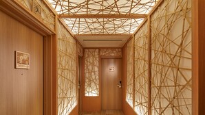 Ein schmaler Korridor mit Holzwänden und einer Decke mit geometrischem Bambusmuster.
