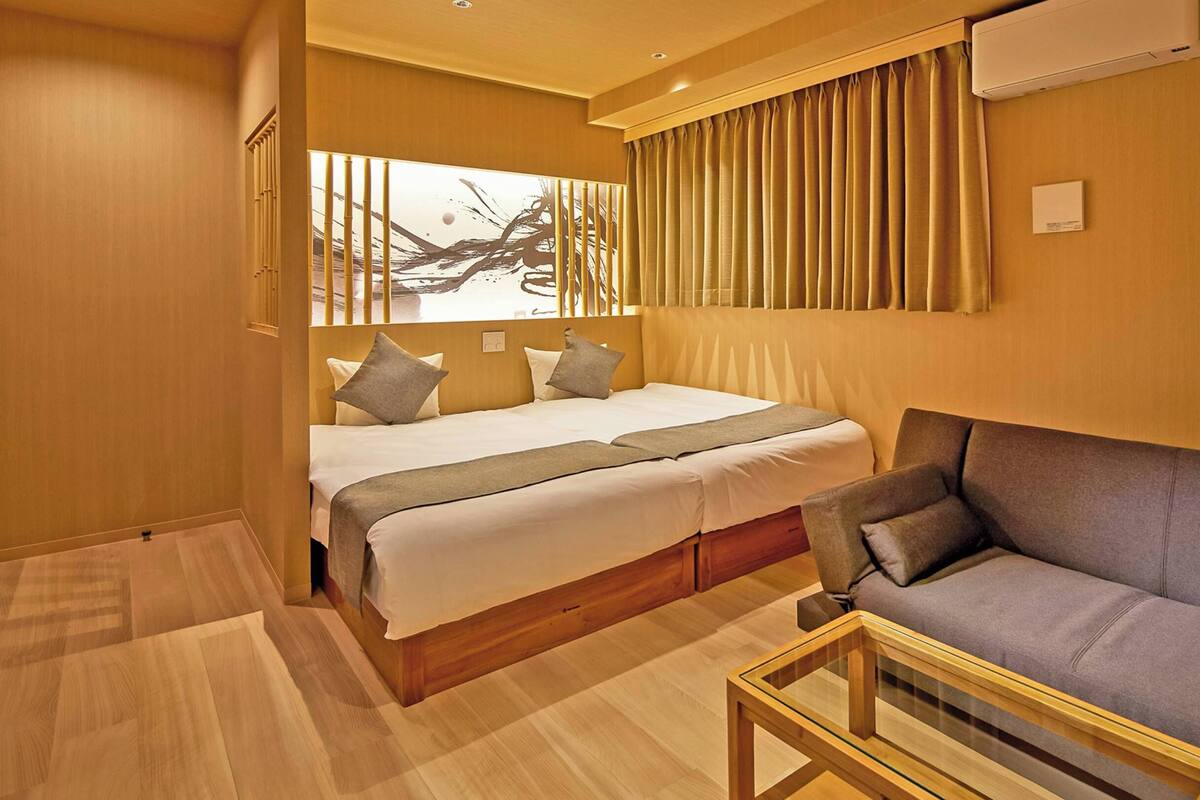 A hotel room with a bed, a sofa, and a small table.