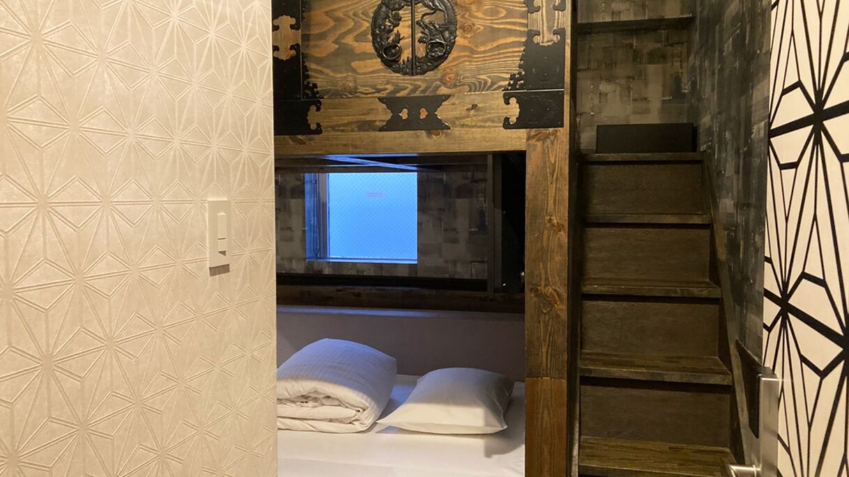 A room with a bed, a window, and a wooden ceiling.