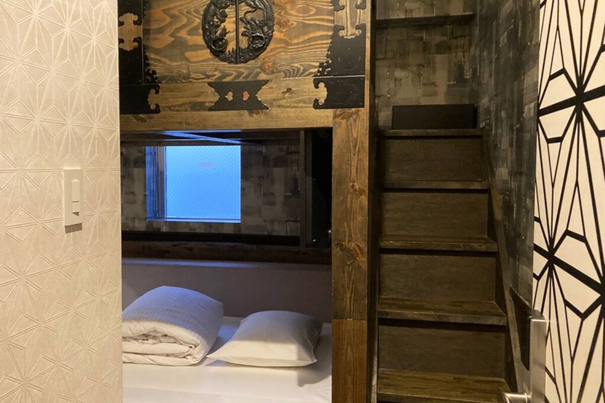 A room with a bed, a window, and a wooden ceiling.