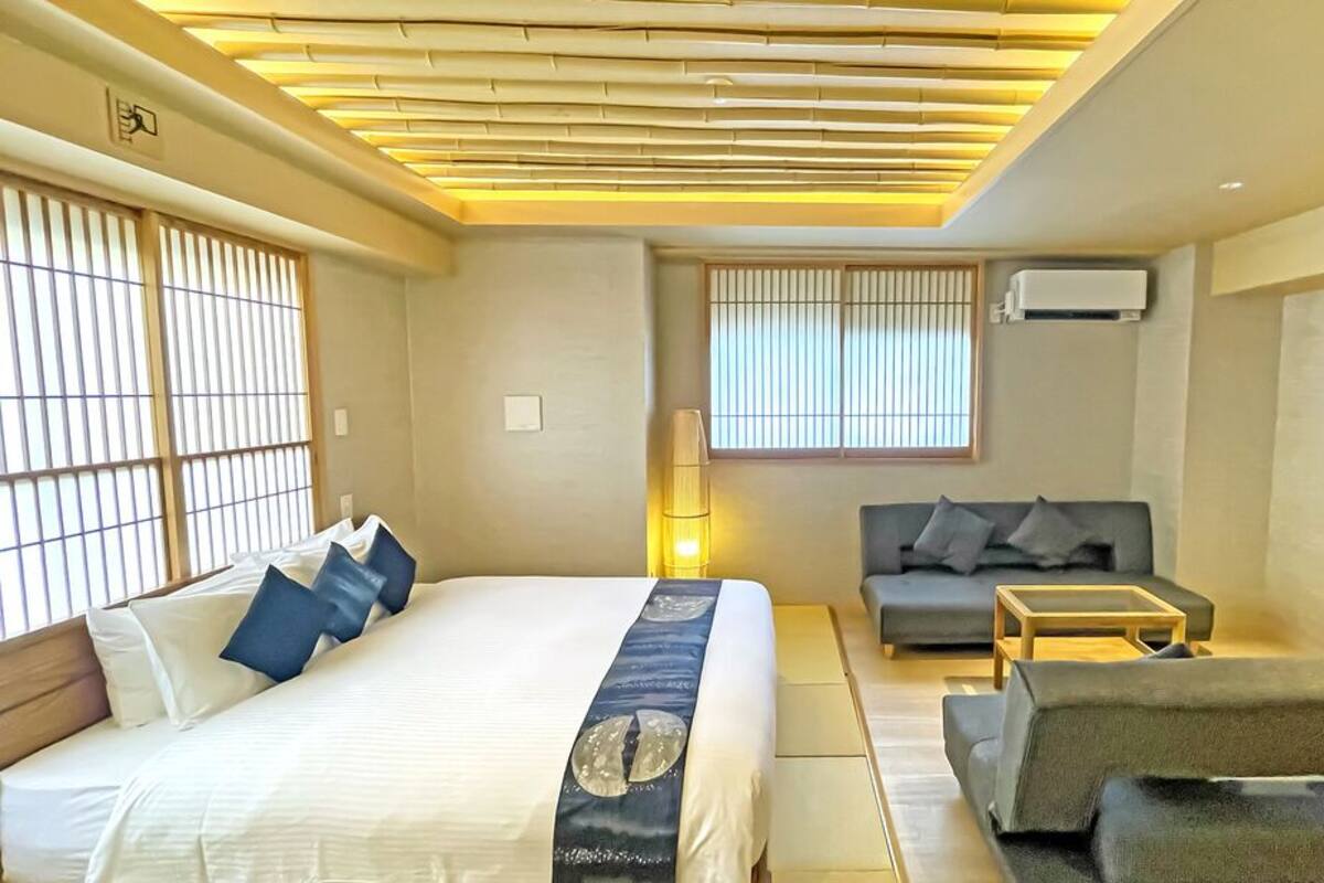 A modern hotel room with a bed, sofa, and a small table.