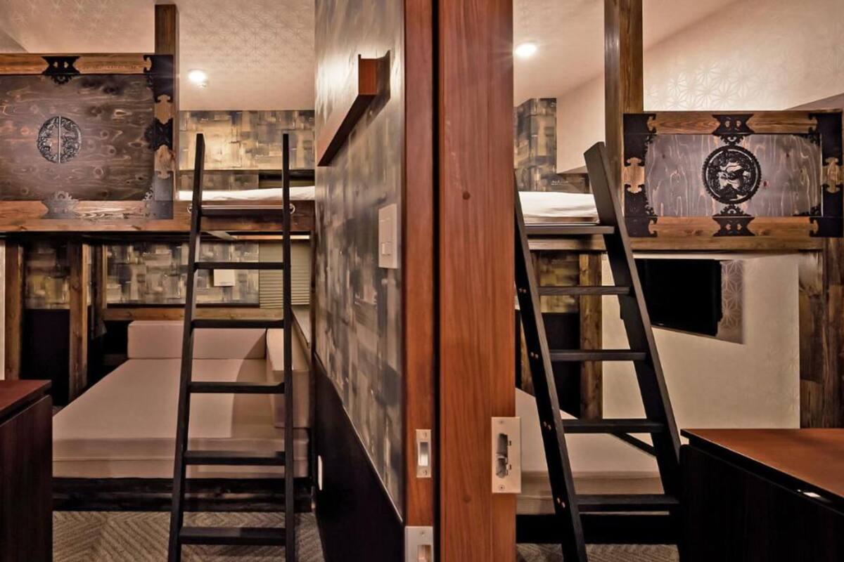 A compact, modern room with bunk beds, a desk, and a ladder.