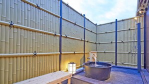 Ein traditionelles japanisches Onsen mit einer Holzbank, einer Steinschale zum Baden und einer Laterne.