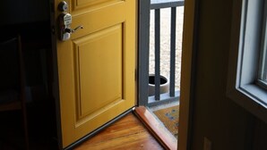 Una puerta amarilla con manija metálica y cerradura, que da a una zona con piso de madera.