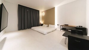 Ein modernes Hotelzimmer mit einem großen Bett, einem Schreibtisch und einem Flachbildfernseher.