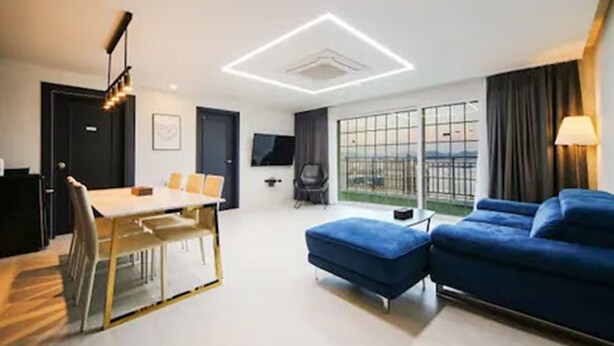 Ein modernes Hotelzimmer mit Essbereich, einer Sofaecke, einem Fernseher und großen Fenstern mit Aussicht.