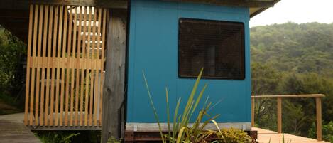 A small, single-story structure with a blue exterior and a wooden deck.