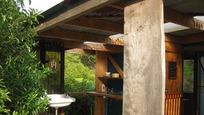 Una terraza de madera con un lavamanos, una silla amarilla y vistas al verdor.