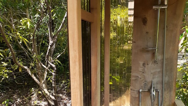 Un cerramiento de ducha exterior de madera con lavamanos integrado.