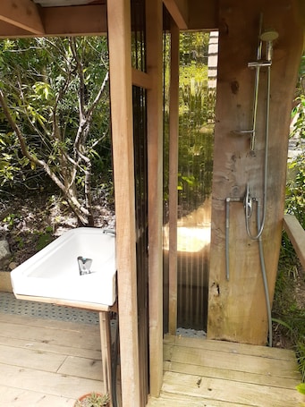 A wooden outdoor shower enclosure with a built-in sink.