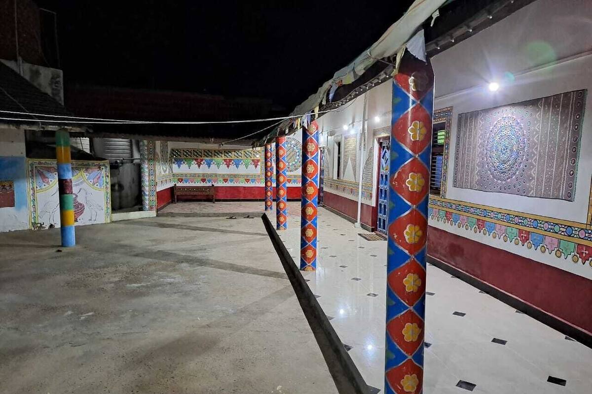 A corridor with colorful pillars and patterned walls, leading to a room with a decorative window.