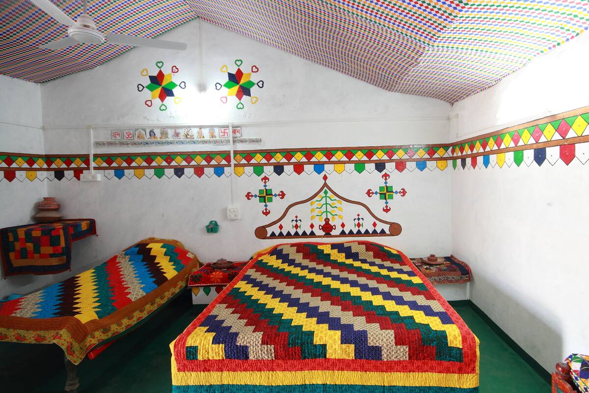 A room with two beds, colorful wall decorations, and a patterned ceiling.