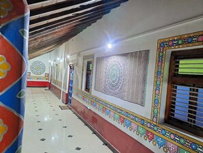 A corridor with patterned walls, a tiled floor, and a ceiling with wooden beams.