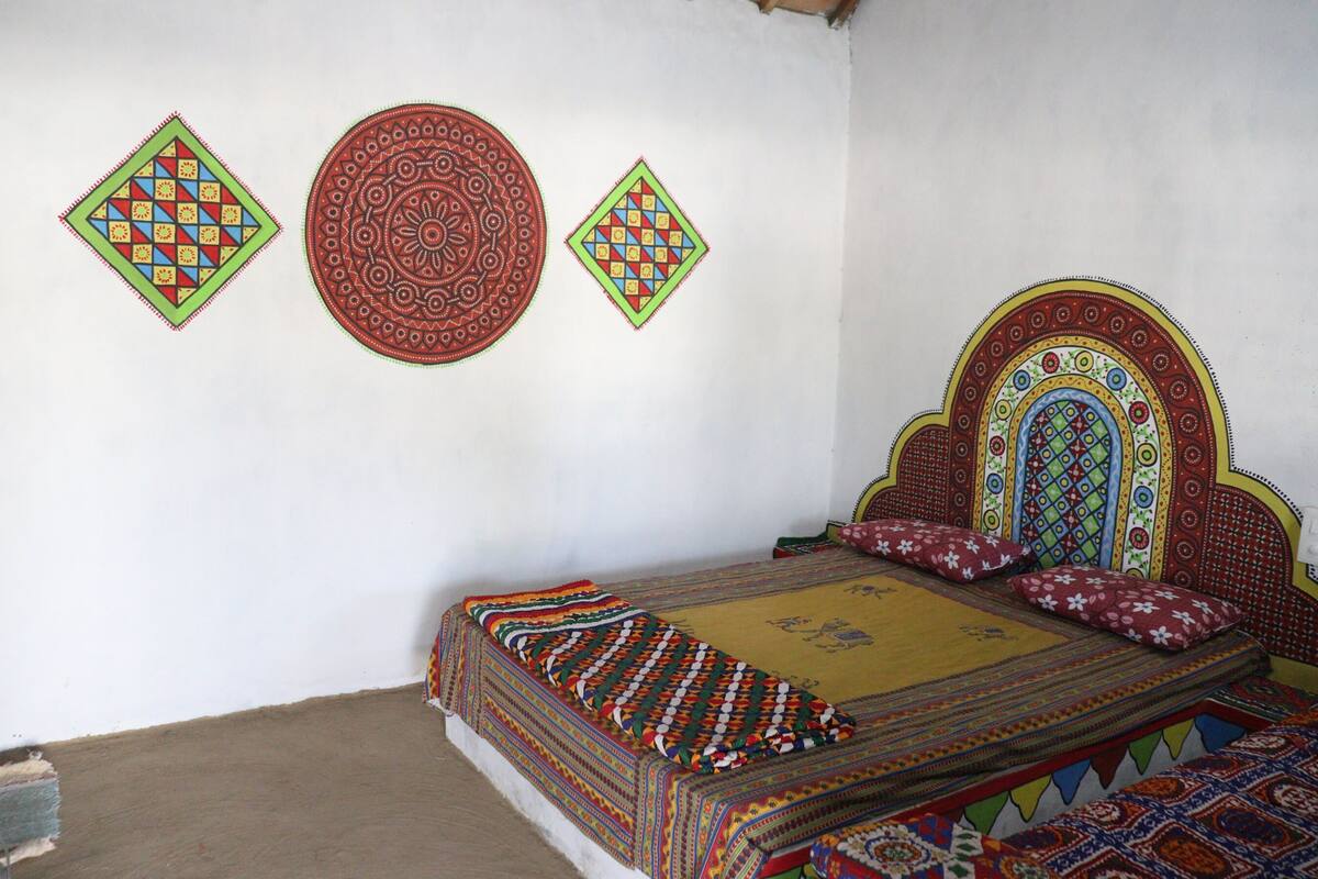 A room with a bed, pillows, a patterned headboard, and three wall decorations.
