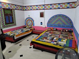 A room with two beds, colorful patterned walls, and a small window.