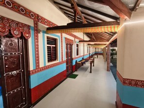 A corridor with traditional patterned doors and walls, wooden benches, and a tiled floor.