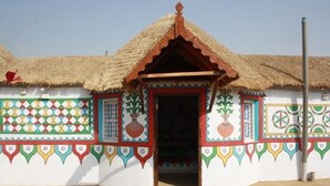 A traditional house with a thatched roof and colorful geometric patterns on the walls.
