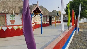 A building with a thatched roof, colorful walls, and a flagpole with flags.