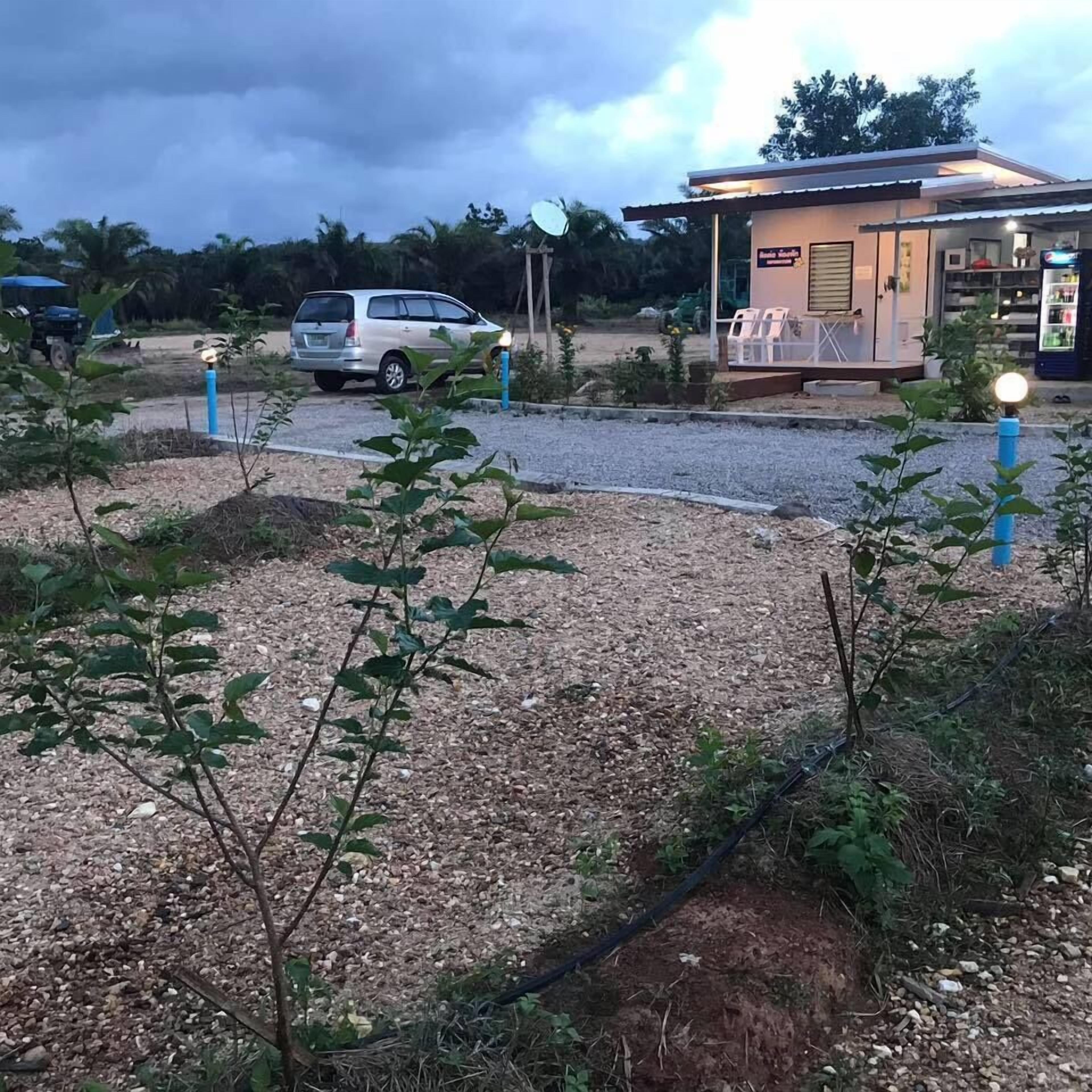 A gravel parking area with a small building, possibly a kiosk or service point, and a parked car.