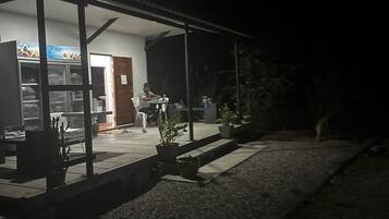 Un espacio al aire libre techado con un refrigerador, plantas en macetas y una zona de estar.