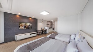 Habitació d'hotel moderna amb un llit gran, un escriptori petit, un televisor penjat a la paret i una cuineta.