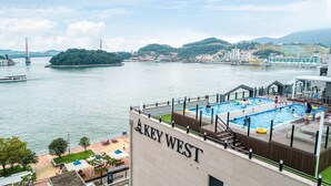 Hotel al costat del riu amb zona de piscina, vistes al riu i un pont al fons.
