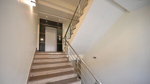 A modern staircase with a metal railing and a door at the top. - Blueberry Inn (Raipur)